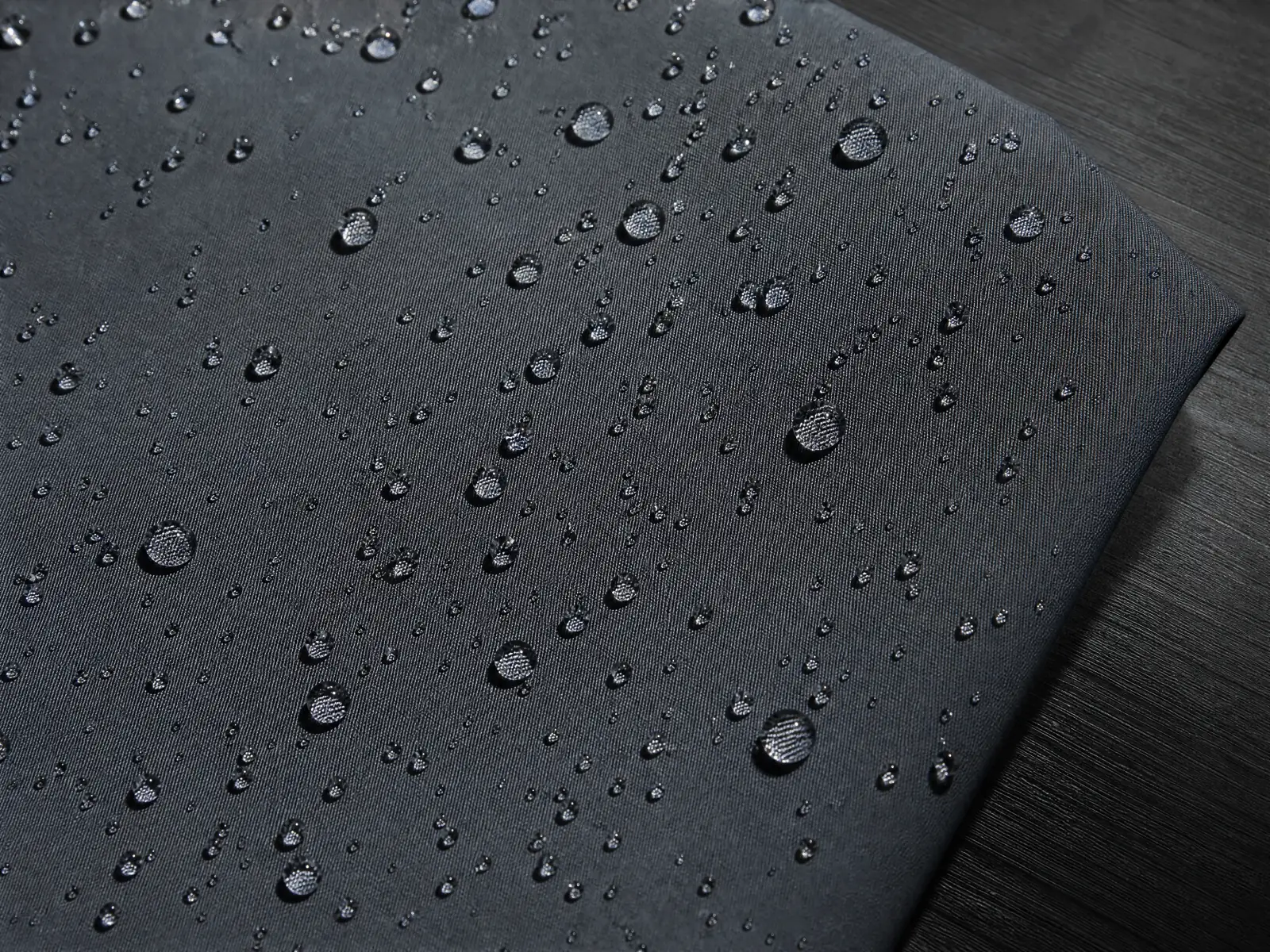 Macro of water beading on tightly woven slate-grey shell fabric