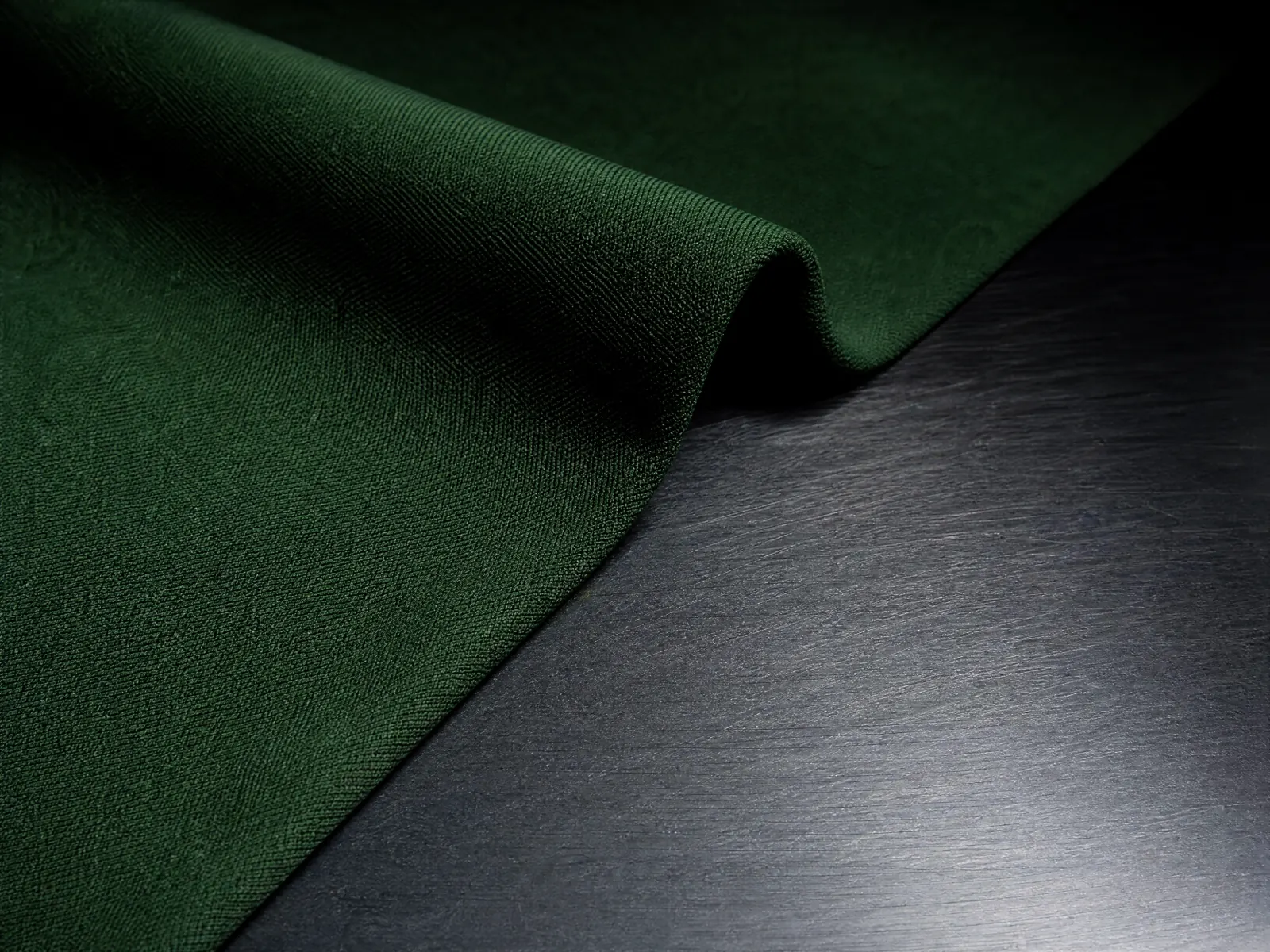 A fold of matte forest-green cloth, the crease lit from behind